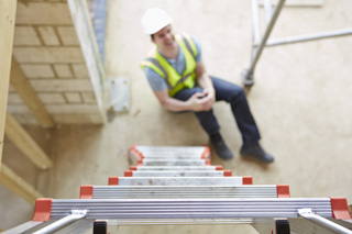 Man who fell from ladder is holding his knee and holding his knee in pain.